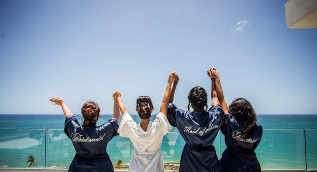 A joyful bridal party with friends in robes celebrates an oceanfront view, creating a memorable pre-wedding moment.